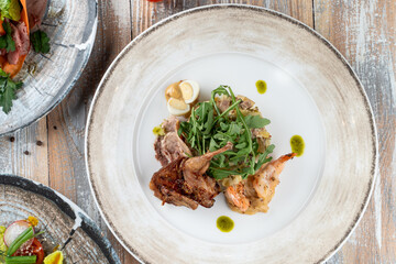 Roasted quail with salad and king prawns as an exquisite dining in a restaurant