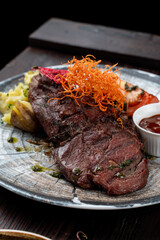 Well-done sirloin steak with mashed potato and chili sauce, close up mouthwatering shot