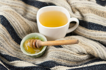 cozy autumn Breakfast with tea in white cup with honey and a warm knitted sweater