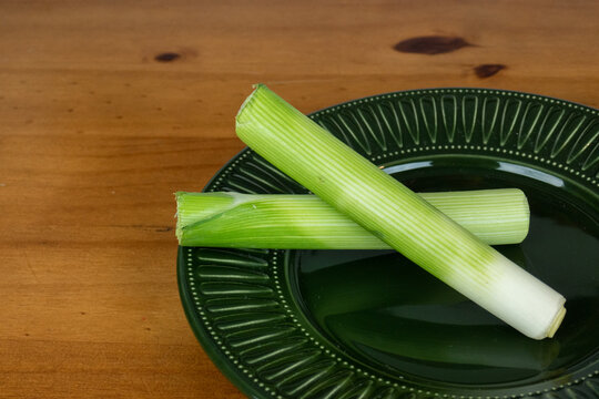 leek overlaid, served in dark green plate on wooden table, close-up photo, with space for text.