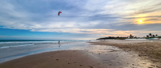 Homem fazendo windsurf na praia durante o pôr do sol