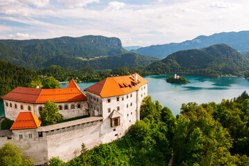 Fototapeta na wymiar Aerial view of mediaeval Bled castle on the cliff of the mountain under lake Bled with turquoise blue water in Slovenia