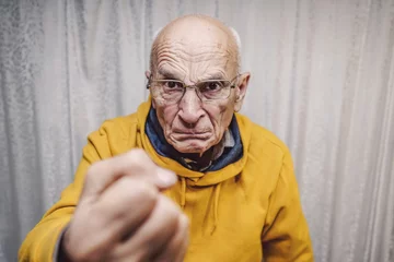 Fotobehang Portrait of angry caucasian man wearing eyeglasses and showing fist © Bonsales