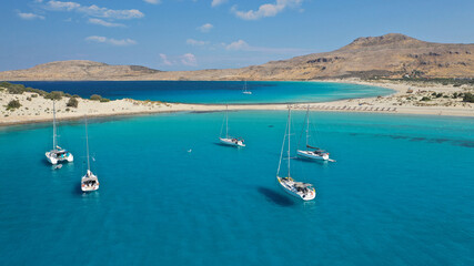 Obraz premium Aerial drone photo of paradise turquoise sandy beach and bay of Simos in island of Elafonisos visited by yachts and sail boats, South Peloponnese, Lakonia, Greece