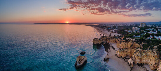 Aerial sunset  view of the beautiful Praia dos Tres Irmaos (Tree Brothers beach) in Alvor, famous...