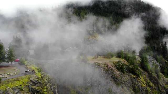 Bird's eye view from drone on breathtaking nature plateau with forested landscape, overhead of stunning scenery evergreen highland during foggy weather
