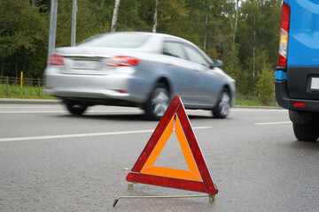 Emergency stop sign on the road in front of a faulty car.