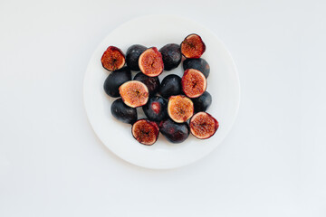 Ripe and sweet figs cut and arranged in a plate on a white background with free space. Fruits and vegetarianism