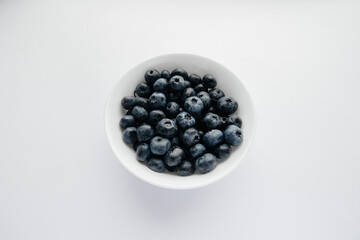 Beautiful ripe blueberries in a glass bowl on a white background. Healthy food, and vitamins.