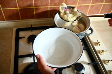 High angle view of a pastry chef takes out cooked dumplings from boiling water into a colander