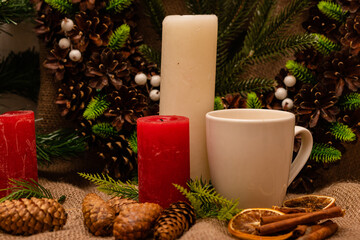 Beautiful Christmas composition of candles, cups and branches of pine needles