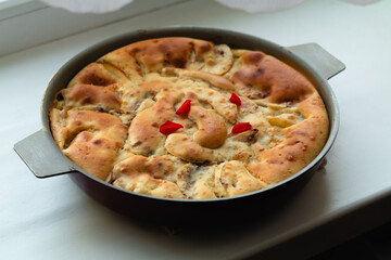 Autumn round apple pie with cinnamon with a golden crust on a light table.