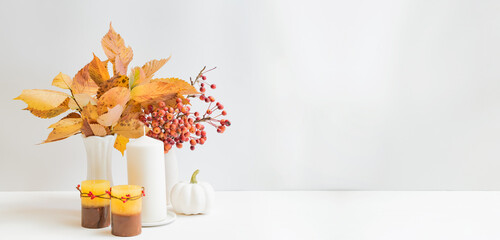 Home interior with decor elements. Colorful autumn leaves in a vase on a light background
