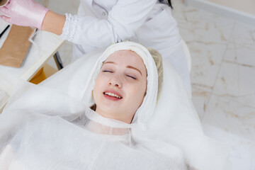 A young girl in a cosmetology office is undergoing facial skin rejuvenation procedures. Cosmetology.