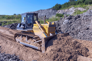 in the process, the bulldozer moves a pile of sand during the construction of a new road