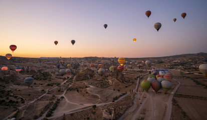 Cappadocia, Turkey: Wide angle aerial panoramic shot of colorful hot air balloons together floating in the sky at early morning sunrise horizon in Goreme national park