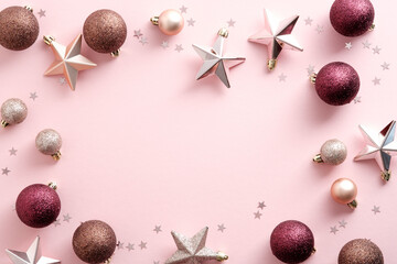 Christmas frame with decorations, balls, stars, confetti on pink background. Flat lay, top view, copy space. Elegant, minimal style.