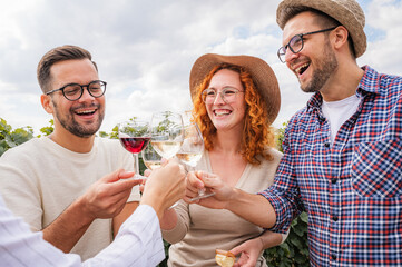 Happy friends having fun drinking wine at winery vineyard - Friendship concept with young people enjoying harvest time together