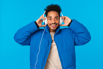 Waist-up portrait happy smiling african american guy listening music in headphones, put earphones...