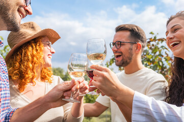 Happy friends having fun drinking wine at winery vineyard - Friendship concept with young people enjoying harvest time together