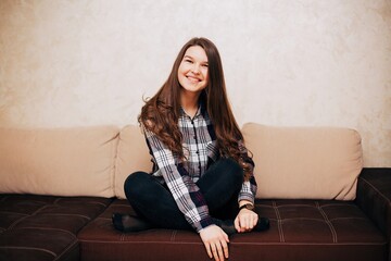 Girl in a cardigan shirt sitting on the couch. Long haired brunette sitting on the couch at home