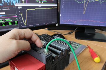 Close-up of a hand restarting a PLC. Cable connection detail. Testing and programming of an...