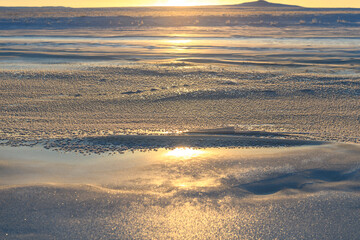 Arctic landscape in winter time. Small river with ice in tundra. Sunset.
