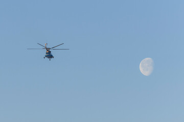 Helicopter flying in the blue sky with moon.