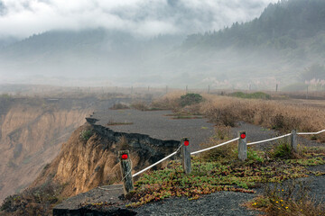 road erosion along California coast with fog and mountains 