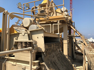 Different sized crushed stone fall out of stone crashing machine. Producing of construction materials at construction site