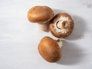Champignon mushrooms on a white wooden background.
