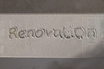 The text of renovation on a dusty laminate board covered with a white suspension from sanding putty...