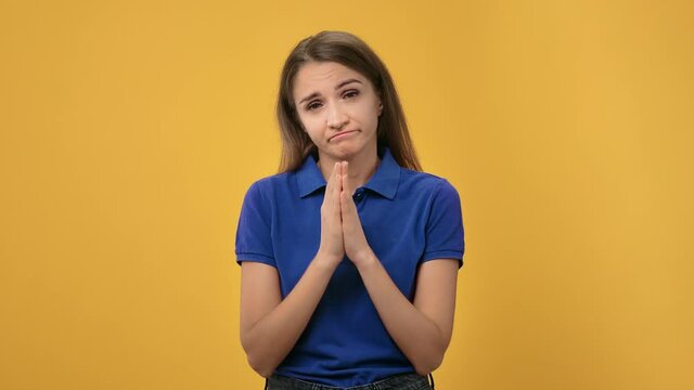 Portrait European blonde woman asking please with united hands posing isolated on orange studio