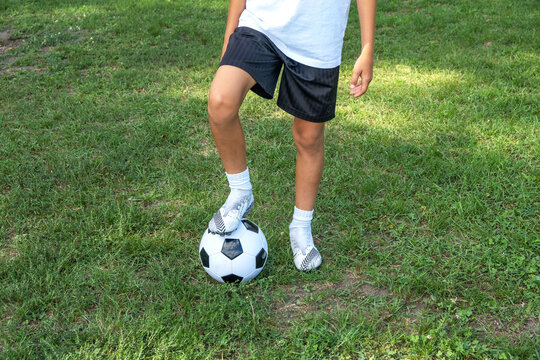 Boy teen puts his leg on ball on soccer field.