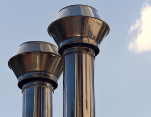 Zwei hoch in den blauen Himmel emporragende, gl&auml;nzende Schornsteine 