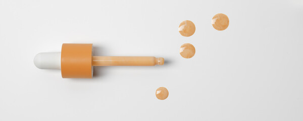 Drops of liquid skin tint serum foundation applied from dropper on white background