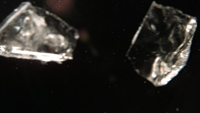Ice Moving Across Screen In Black Space. Ice Falling And Bouncing. VFX Plate For Texture.  Dark Background In Slow Motion