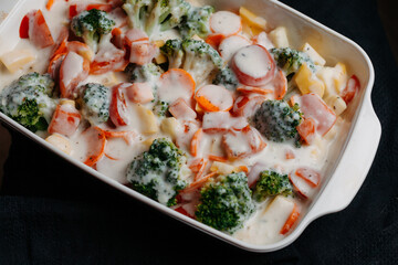 Sliced vegetables in a white ceramic bowl with grated cheese, close up