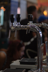 Fototapeta na wymiar Beer taps closeup at the craft beer festival in Ukraine, the city of Lviv. Vertical photo, blurred background.