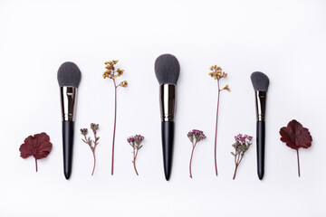 Makeup brushes with wild flowers isolated on a white background depicting natural beauty products.