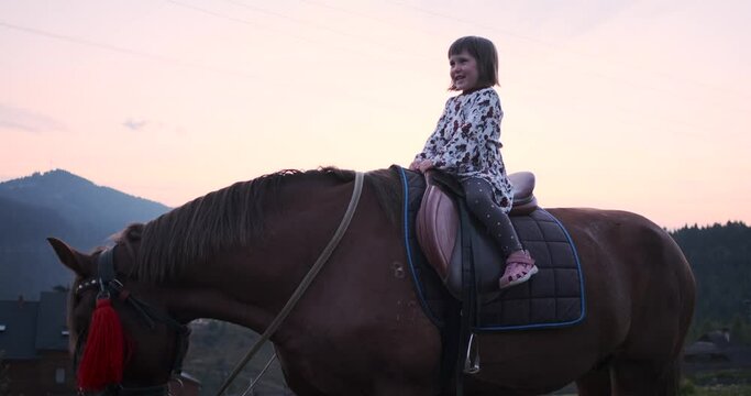 Little girl riding horse in countryside stud farm