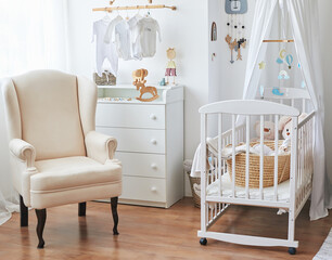 Scandinavian style white interior  bedroom, nursery. Baby cot with ​canopy. Wooden shelves and toys. Armchair in children's room