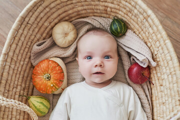 Newborn baby boy lies in wicker cradle with pumpkins and apples. Happy motherhood and fatherhood. Maternity hospital and clinic. Father and mother day. Autumn background. Thanksgiving, halloween