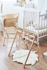 Fototapeta na wymiar Scandinavian style white interior children's room, bedroom, nursery. Baby cot with ​canopy. Wooden shelves and toys. Children's developmental simulator. 
