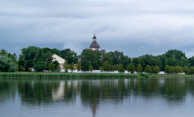 Fototapeta na wymiar Lake overlooking the old Farny Church in Nesvizh, Belarus. Beautiful summer landscape with architectural elements.