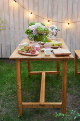 Summer garden background. Bouquet of flowers hydrangeas and  cup of tea on table. Good cozy morning. Picnic in nature. Mother's day greeting card. Celebration