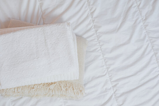 Home Textiles Flatlay. A Stack Of Towels Lies On A White Bed