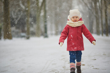 Adorable toddler girl on a day with heavy snowfall