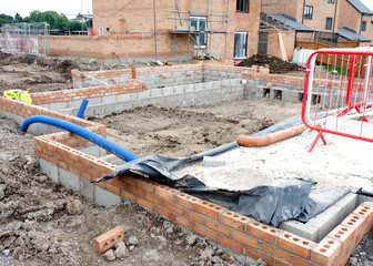 New house construction in progress on housing development site with underground part of the wall...