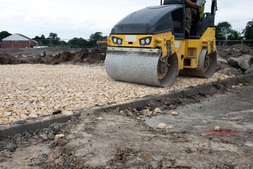 Drum Ride On Roller compacting freshly laid tarmac during roadworks and new footpath construction